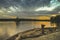 Structured blue cloud on a countryside lake during the sunset on a wooden bench through the orange horizon in beatiful summer day