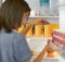 Struggling with OCD. Young woman organising the contents of her fridge carefully.