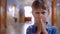 Struggling teen boy concealing face in school corridor, blurred background, space for text