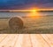 Stubble field at sunset with old wooden planks floor on foreground