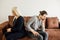Stubborn angry husband and wife, spouses sit separate on sofa at home ignore each othe
