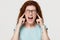 Stubborn angry redhead girl sticking plug fingers in ears screaming