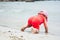 Stubborn child crawling towards water on beach during summer holidays
