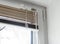 Stuck blinds.Adjusting the white blinds in height use a cord.Half-open metal blinds mounted on a plastic window.