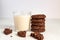 Stuck of chocolate brownie cookies and glass of coconut milk on wooden background. Homemade pastry