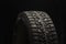 Studded winter tire, side view. Close-up on a black background