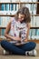 Student against bookshelf using tablet PC on the library floor