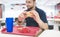 Student with an appetizing burger and fast food tray sits at the fast food restaurant table