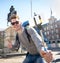 Student backpacker tourist taking selfie photo with stick and mobile phone outdoors