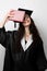 Student with book in graduation robe and cap ready to finish college. Future leader of science. Academician young woman