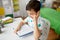 Student boy in earphones reading book at home