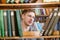 Student chooses a book on a shelf in the library