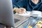 A Student with earphones taking notes in notebook while learning online via laptop at home, depth of field. A Young female virtual