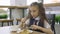 Student elementary school in a school uniform sitting at a table in the school cafeteria and eat.