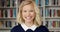 Student face of a young woman student smiling and laughing while standing in a library at university. Portrait of