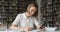 Student girl holds cell phone jotting information in copybook
