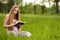 Student girl sit on lawn and reads textbook.