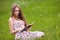 Student girl sit on lawn and reads textbook.