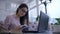 Student girl writes notes sitting at table with books and laptop in cafe during e-education