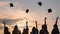 Student graduates toss their caps at sunset.