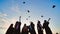 Student graduates toss their caps at sunset.