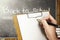 Student hands holding clipboard and writing in the classroom with piles of books and blackboard background