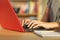 Student hands writing in a red laptop at home