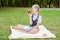 Student happy smiling with apple in hand. schoolgirl sitting on a blanket in a park with textbooks