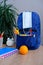 Student home office table with blue schoolbag, books, orange, colored notebooks, pencils in glass, chalk board, globe, white alarm