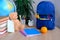 Student home office table with blue schoolbag, books, teddy bear, colored notebooks, pencils in glass, chalk board, globe, white