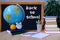 Student home office table with white alarm clock, books, orange, colored notebooks, pencils in glass, chalk board, globe, white