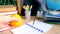 Student home office table with white alarm clock, books, orange, colored notebooks, pencils in glass, chalk board, globe, white