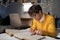 Student lying on a bed and studying with focus and concentration. Young man preparing for exam reading books and writing