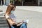 Student in a mask with books and a backpack on a bench in the park in summer, protection from covid teenagers and children