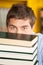 Student Peeking Over Piled Books In University