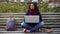 Student pondering over project while working on laptop, sitting on bench outdoor