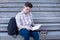 Student preparing for the test on the stairs of the university. Young guy reads a lecture before the final exam