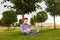 Student reading book sitting in the park under tree on the grass