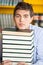 Student Resting Chin On Stacked Books In Library