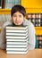 Student Resting Chin On Stacked Books At Table In