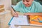 Student's hand holds a pencil, paints the perimeter of a rectangle drawn in notebook, doing homework on geometry at