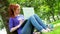 Student sitting against a tree using her laptop