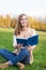 Student sitting on green grass with opened blue book