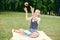 Student is smiling happily and is holding a red apple overhead. schoolgirl sitting on a blanket in a park with books