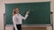 A student stands near the blackboard on which mathematical formulas are written.