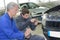 Student and teacher mechanics changing car headlight in workshop