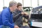 Student and teacher mechanics changing car headlight in workshop