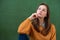 Student thinking and leaning against green chalkboard background. Pensive girl looking up. Caucasian female student portrait.