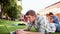 Student using laptop with classmates sitting behind on grass