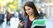 Student walking and checking phone in the street